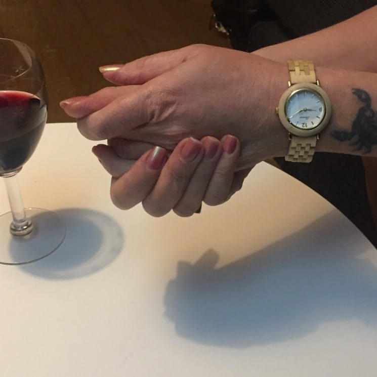 Ett glas rött vin på bordet och två händer med rosa nagellack. Ett armbandsur av lönnträ på armen. Unik stil, unika material för den miljömedvetna...